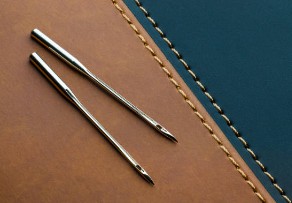 Sewing machine needle kept on a flat leather panel
